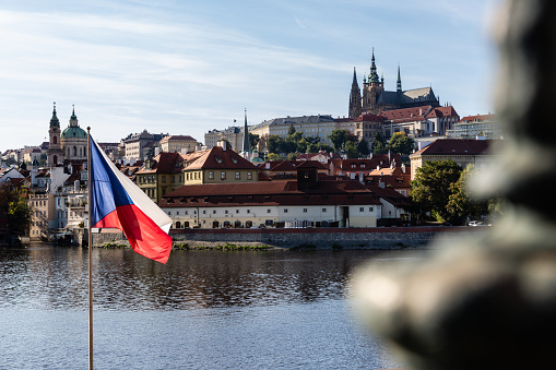 Prague, Czech Republic (Czechia) - October 1, 2021: Prague Castle viewed from the bank of the Vltava River with the Czech flag flying in the foreground.