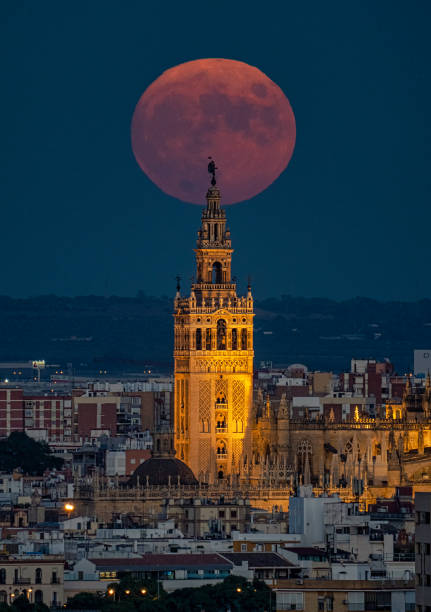 Full Moon and Giralda FULL MOON RISES BEHIND THE GIRALDA TOWER OF SEVILLA seville stock pictures, royalty-free photos & images