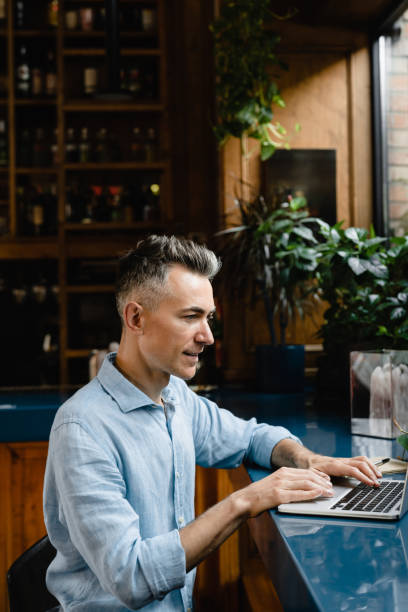 istock Middle-aged caucasian businessman boss freelancer self-employed man working on distance remotely on laptop, e-learning, watching webinars online at the bar counter cafe. 1345013933