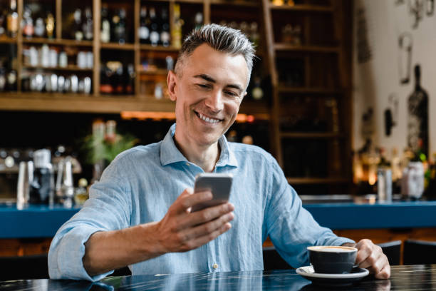 istock Smiling confident caucasian mature businessman freelancer boss using cellphone for surfing net, social media, e-banking, working remotely while drinking coffee in cafe restaurant 1345015005