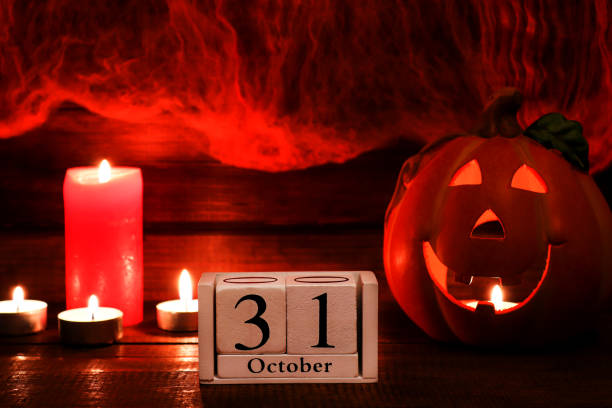 istock Halloween card with copy space for congratulation. Calendar dated October 31, Jack-o-latern and candles against the background of a cobweb. Selective focus 1345015951