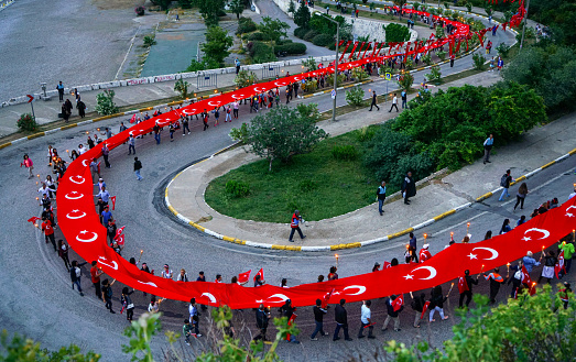 Antalya, Turkey - May 5, 2017: Crowd of Turkish people carrying a long Turkish flag on a National day in Antalya, Turkey