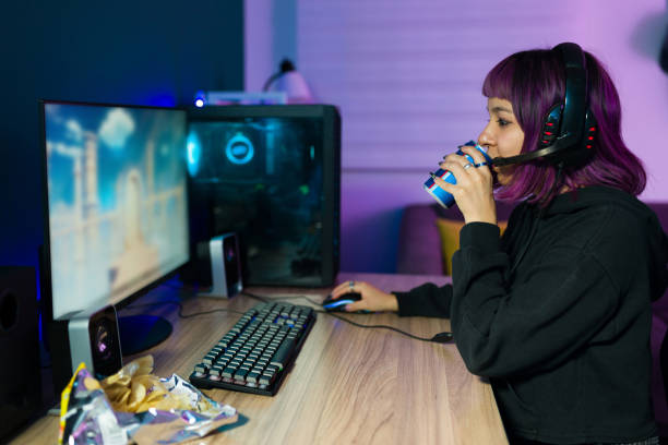 Profile of a young woman drinking an energy drink Energy drink. Latin female gamer drinking a soda can while playing video games on her computer energy drink stock pictures, royalty-free photos & images