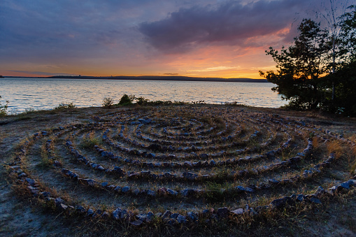 Spiral labyrinth made of stones on the coast at the sunset