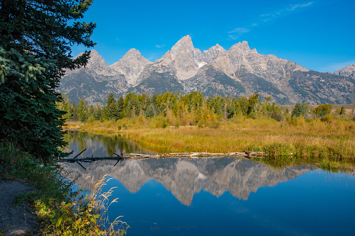 Autumn landscape scene of Snake river reflections under Grand Teton peaks at the national park in Wyoming in western USA. Nearest towns are Jackson Hole, Moran and Dubois, Wyoming.