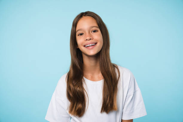 cheerful caucasian schoolgirl teenager pupil student smiling with toothy smile looking at camera isolated. cutout portrait in blue background - meisjes stockfoto's en -beelden