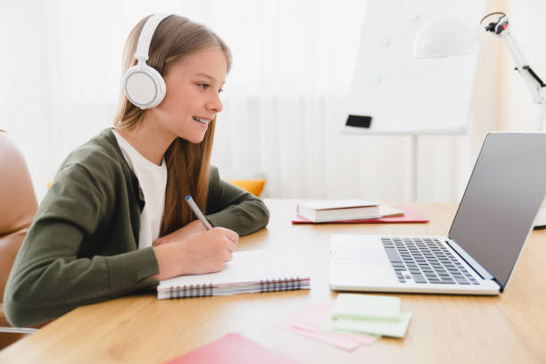 istock Distance remote education e-learning. Young caucasian schoolgirl student pupil doing homework studying from home using laptop and headphones, listening to online classes lessons. 1345027817