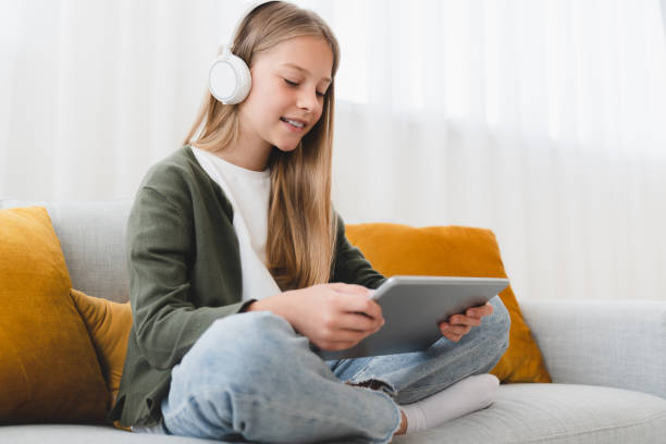 kaukaska uczennica nastolatka córka używa cyfrowego tabletu do oglądania filmów, słuchania muzyki w słuchawkach, surfowania po mediach społecznościowych, e-learningu online z domu. - kindle e reader book reading zdjęcia i obrazy z banku zdjęć