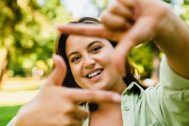 istock Caucasian young smiling woman posing looking at camera on smart phone while walking in park, doing selfie photo image 1345029441