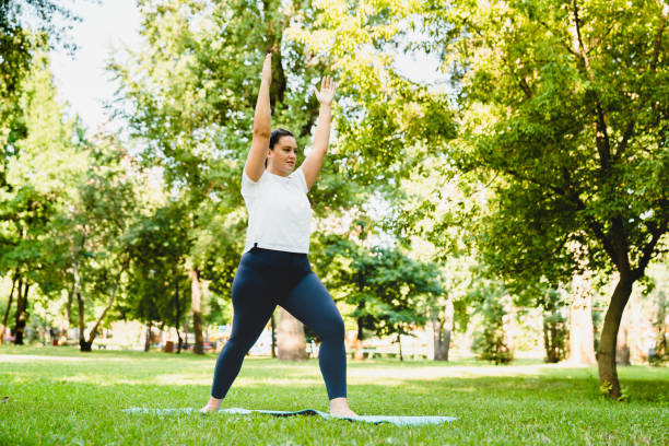 odchudzające spalanie kalorii ćwiczenia. kaukaska pulchna młoda kobieta sportowiec w ubraniach fitness uprawia jogi na macie fitness na świeżym powietrzu w parku. - healthy lifestyle yoga vitality flexibility zdjęcia i obrazy z banku zdjęć
