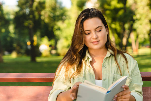 istock Caucasian young woman student freelancer reading book novel, doing homework, preparing for test exam lesson sitting in college university park bench 1345038717