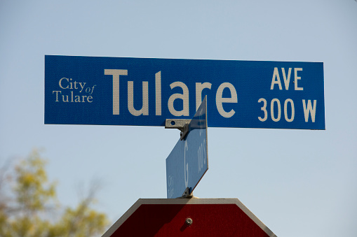 Tulare, California, USA - July 14, 2021: Morning light shines on a Tulare Avenue street sign.