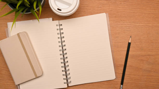 istock Top view of Simple study desk with blank notebook pages on wooden background 1345052153