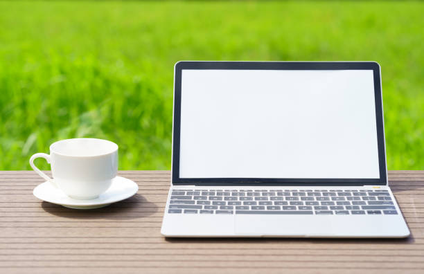 istock laptop and cofree cup on wood table agent grass field 1345053742