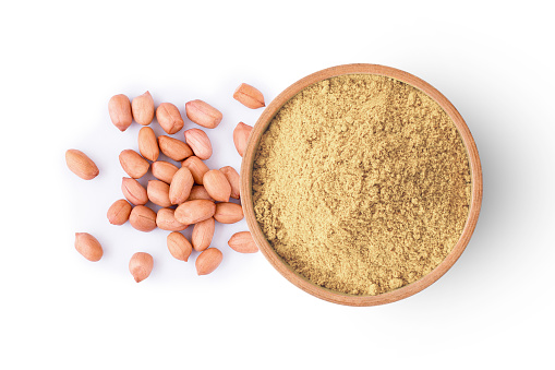 Peanut powder in wooden bowl isolted on white background. Top view. Flat lay.