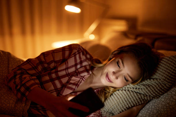 istock Beautiful young woman using mobile phone in bed 1345055249