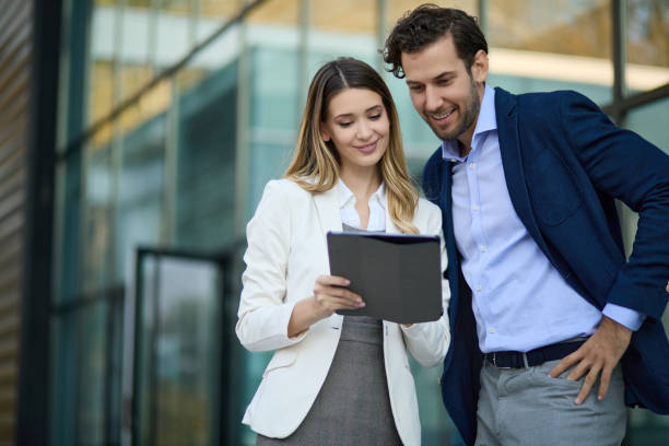 istock Business couple working online outdoors on a tablet computer 1345055996