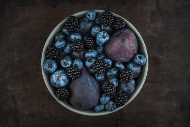 Dark berries and fruits in the bowl on the rustic background. Shot from above. Selective focus.