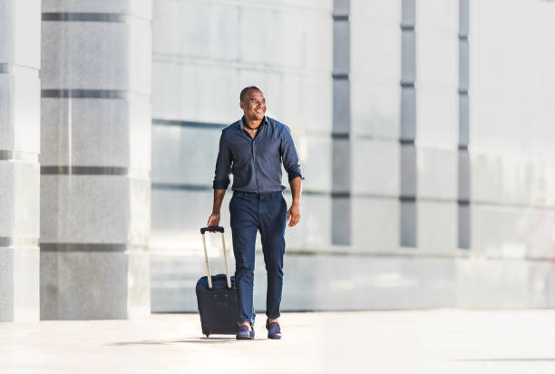 istock Happy black businessman pulling his suitcase on the street. 1345061125