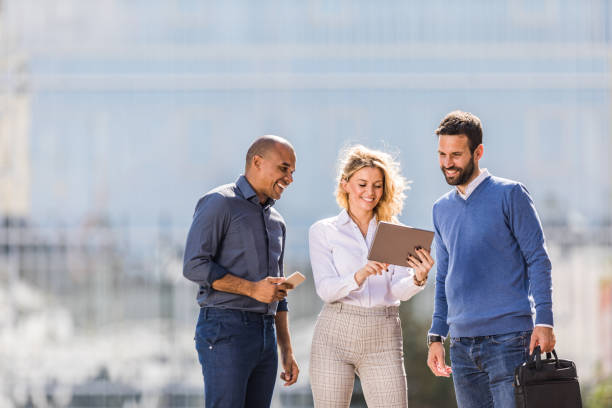 istock Happy business team cooperating while using touchpad on the street. 1345061837
