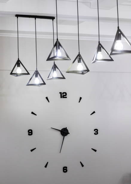 istock Minimalistic design of a wall clock with black numbers and a light bulb 1345064024