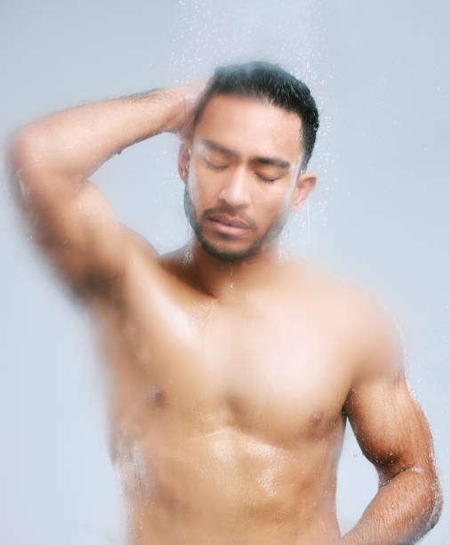 istock Studio shot of a handsome young man taking a shower against a grey background 1345067306