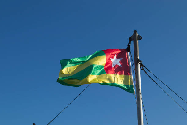 istock Togo national flag waving against blue sky 1345071539
