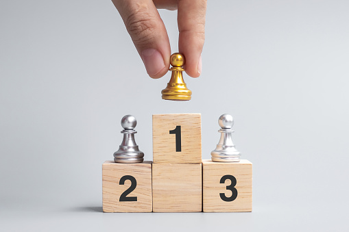 hand holding top of golden chess pawn pieces or leader businessman. victory, leadership, business success, team, recruiting, and teamwork concept