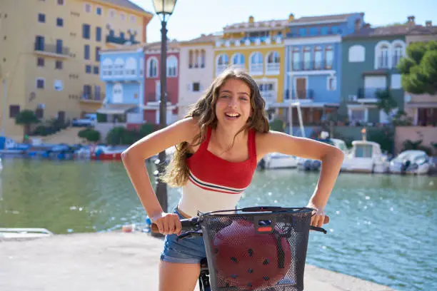 Girl riding a bike smiling in a Mediterranean port