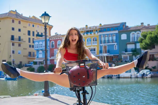 Acrobatic girl riding a bike in a Mediterranean marina port open split legs
