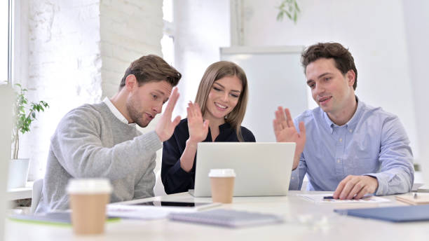 istock Cheerful Creative Team doing Video Chat on Laptop 1345078070