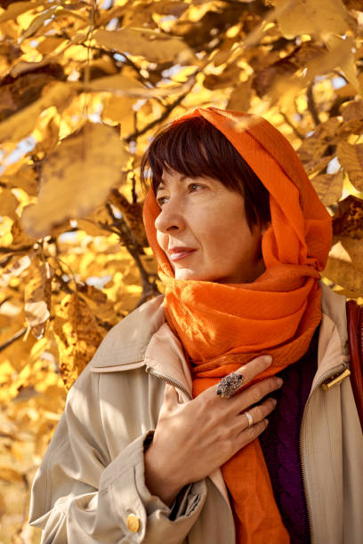 istock Lady in orange scarf walking in the park 1345080047