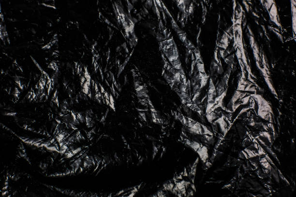 istock Crumpled Black Plastic Bag texture background. Glossy polyethylene overlay 1345080154
