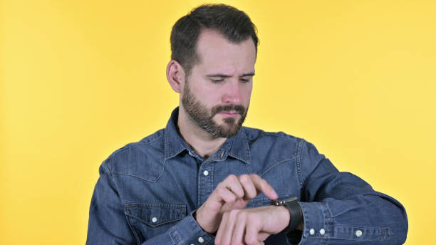 istock Portrait of Professional Young Man using Smartwatch, Yellow Background 1345082835