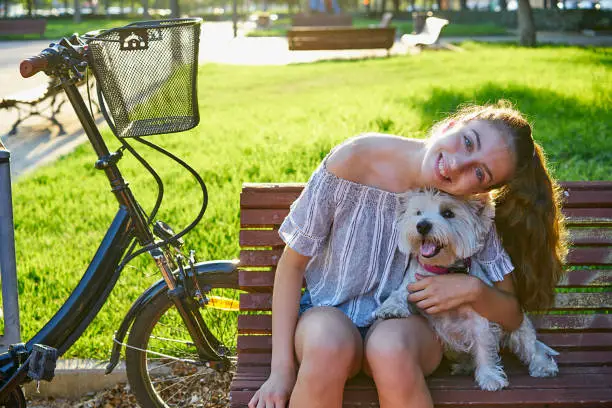 Girl with dog sitting in a park bench with turf grass background outdoor