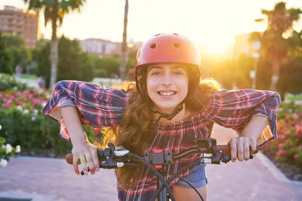 Girl portrait on bicycle with helmet smiling happy at the flowers park outdoor