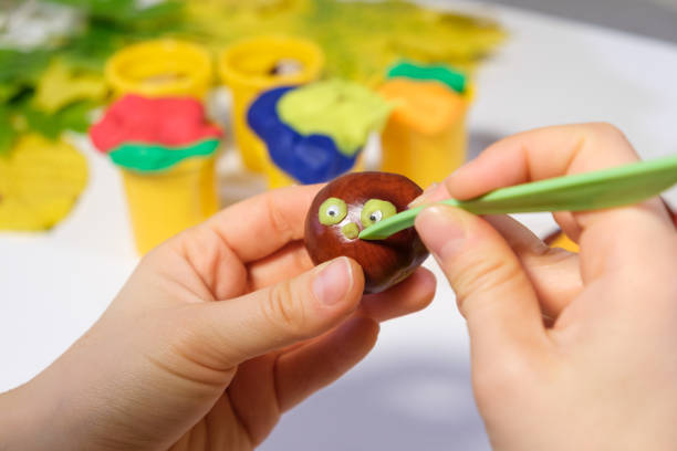 istock A woman creates a muzzle from dough for sculpting on chestnut for handicraft caterpillars 1345085587