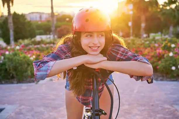Girl portrait on bicycle with helmet smiling happy at the flowers park outdoor
