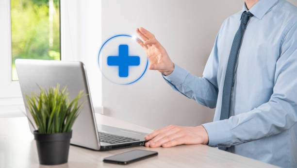 istock Businessman hold virtual plus medical network connection icons. Covid-19 pandemic develop people awareness and spread attention on their healthcare. 1345087343