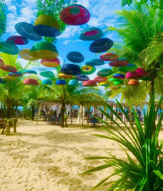 Beach at Itaparica island, Salvador Bahia, Brazil with colorful straw baskets in the sky