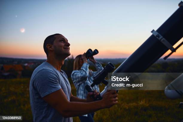 Couple Stargazing Together With A Astronomical Telescope Stock Photo - Download Image Now