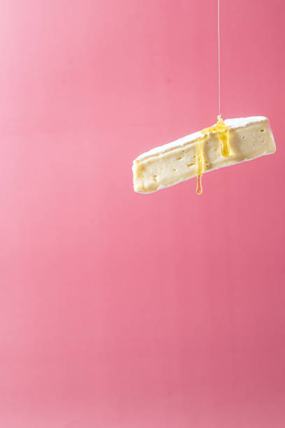 Brie cheese with honey on a pink background. Flying cheese