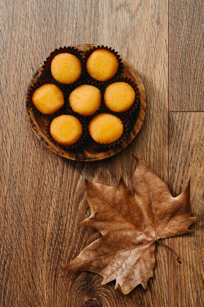 high angle view of some yemas de Santa Teresa or yemas de Avila, a confection typical of Spain, in a wooden plate and an autumn leaf on a wooden table