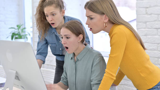 istock Young Female Designers in Shock Reacting to Failure on Desktop 1345092018
