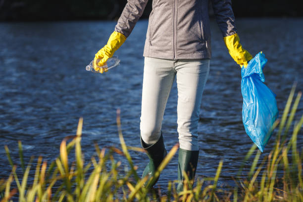 Environmental volunteer cleaning water in nature from plastic waste