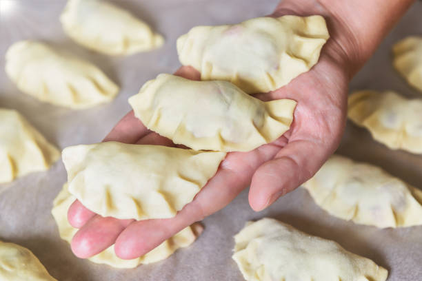 Making dumplings filled with sour cherry with sugar, hand holding freshly made dumplings