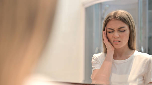 istock Woman Looking in Mirror and having Headache 1345097283