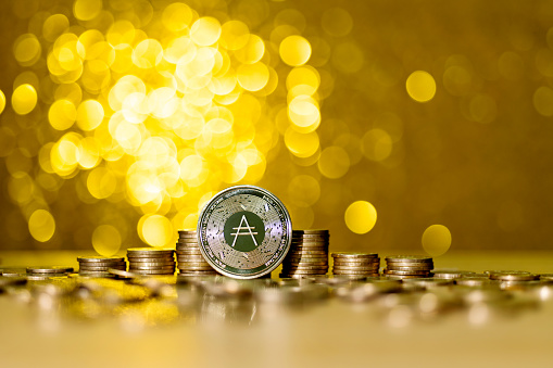 Fujian, China - August 26, 2021: Heap of Cardano coins on shiny golden background.