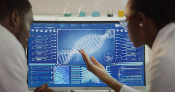 African ethnicity scientists studying DNA samples. Computer screens with DNA sequences. Discussing stock photo