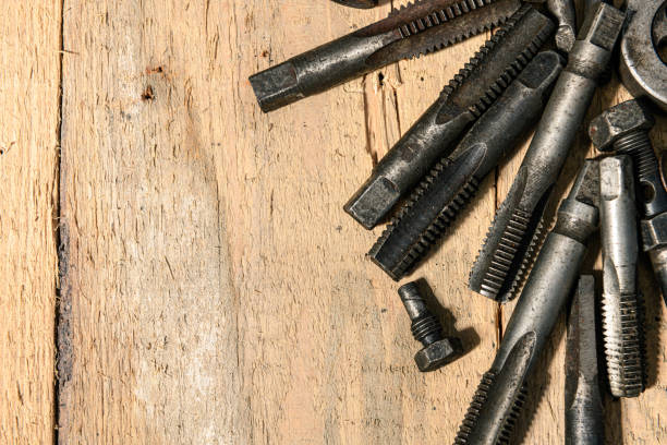 Old vintage drills and threading die tools on a wooden background